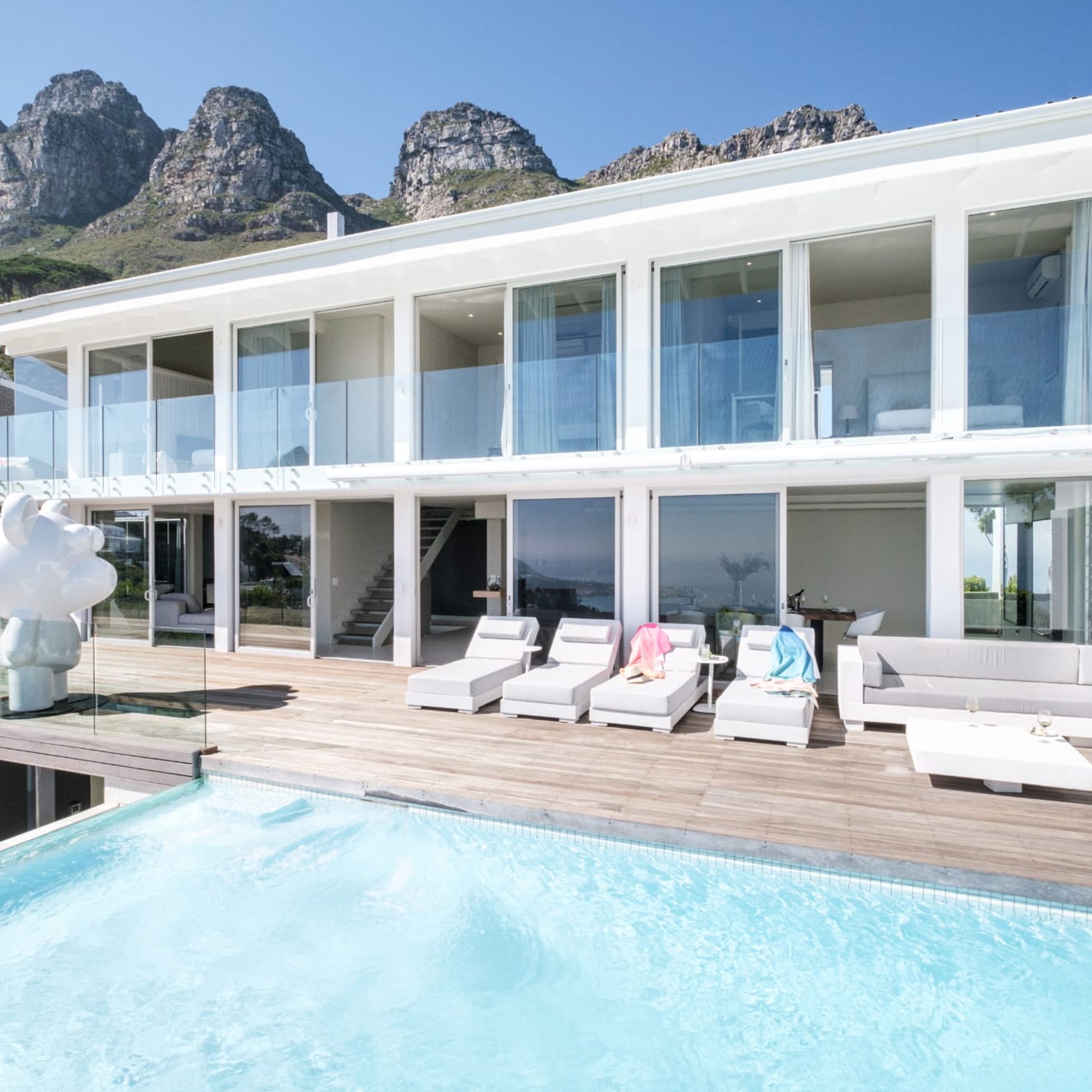 Ein modernes Gebäude mit Pool, weißen Möbeln und Blick auf die Berge.