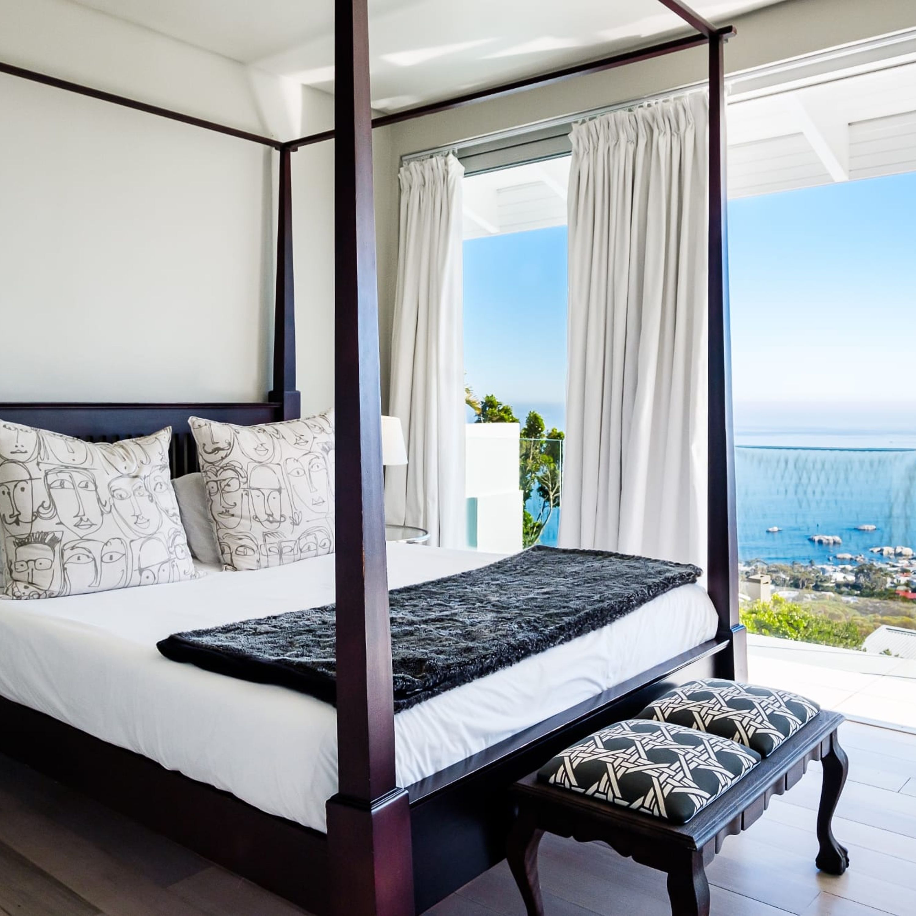 A four-poster bed with a view of the sea and a balcony.