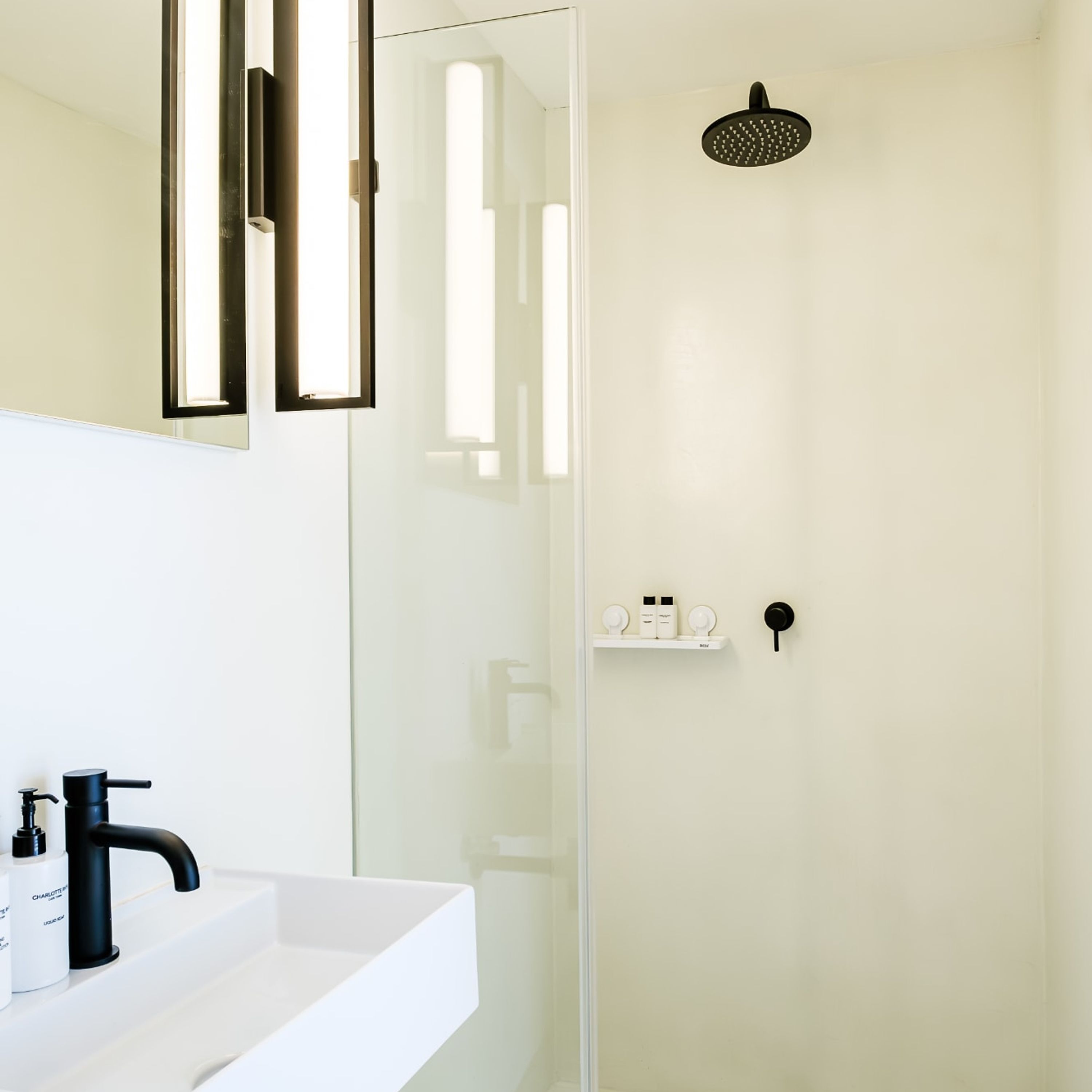 A modern bathroom with a white sink, black faucet, and a glass-enclosed shower area.