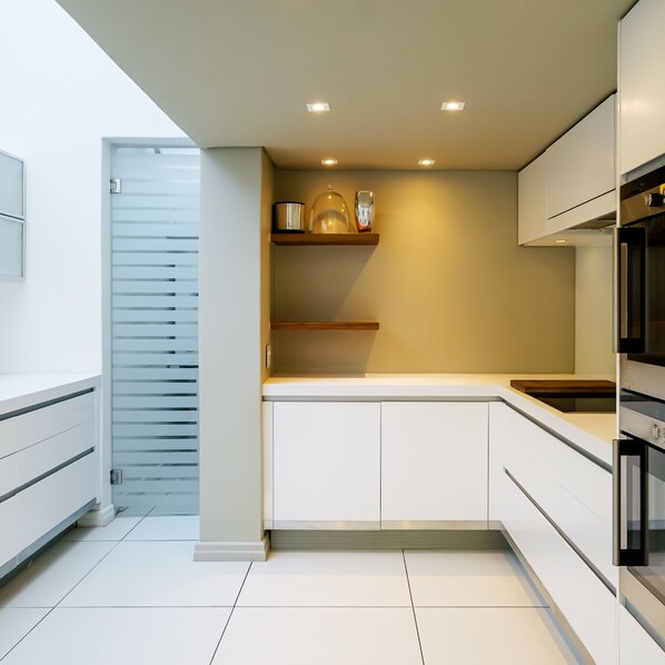 Une cuisine moderne avec des meubles blancs, un plan de travail en bois et des appareils électroménagers intégrés.