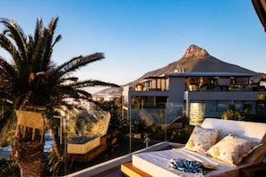 A modern hotel room with a bed, a view of a mountain, and a pool area. - Stylish Penthouse w Private Pool and Parking Houghton Penthouse (Cape Town)