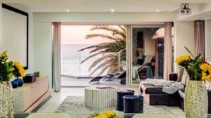 Een moderne woonkamer met een glazen salontafel, een schaal fruit en uitzicht op de oceaan.