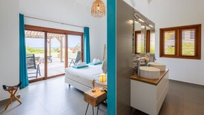 A modern hotel room with a bed, a desk, and a bathroom with two sinks. - Gosa Di Bida I Private Pool (St. Marie)