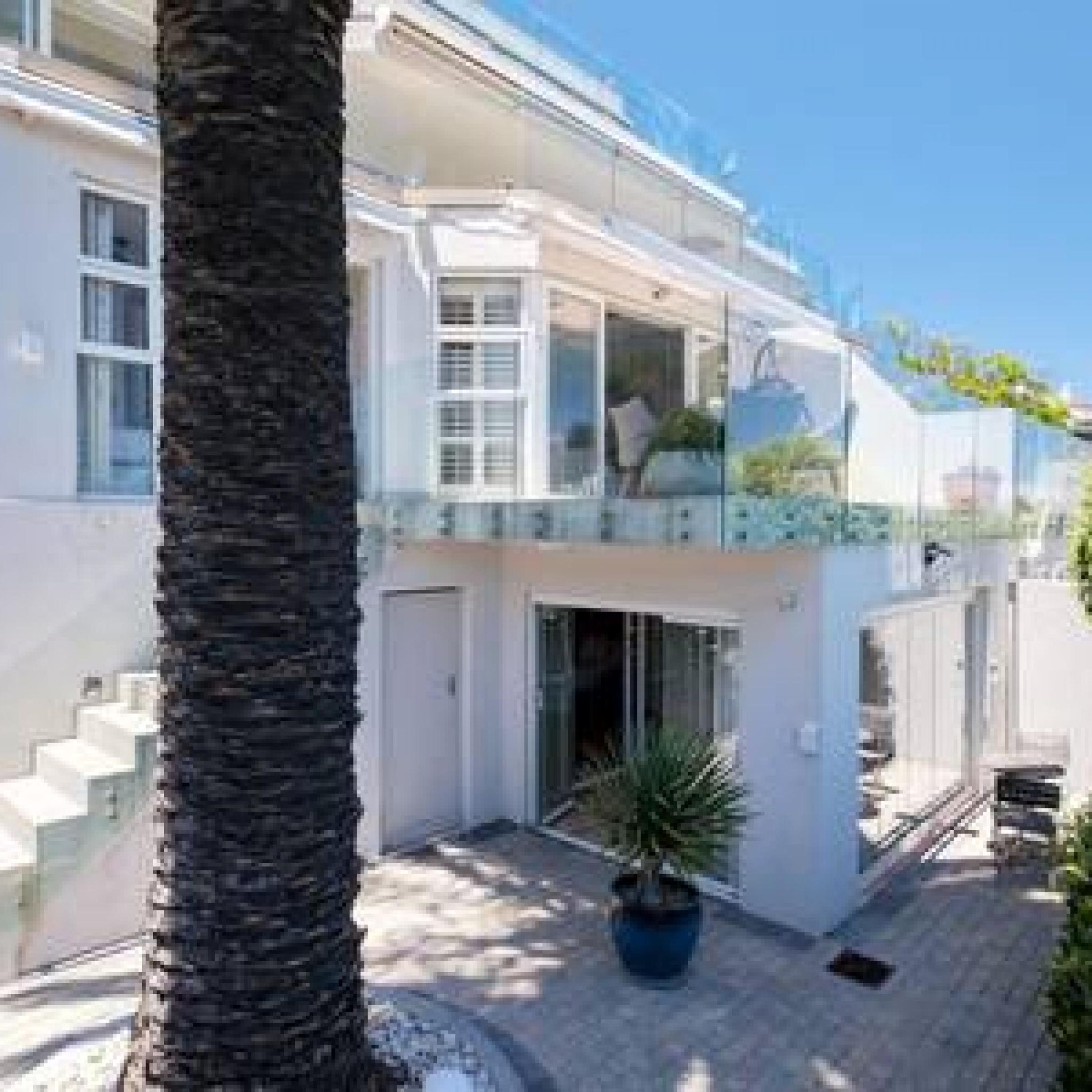 Une maison moderne à deux étages, dotée d’un balcon, d’un escalier et d’une plante en pot.