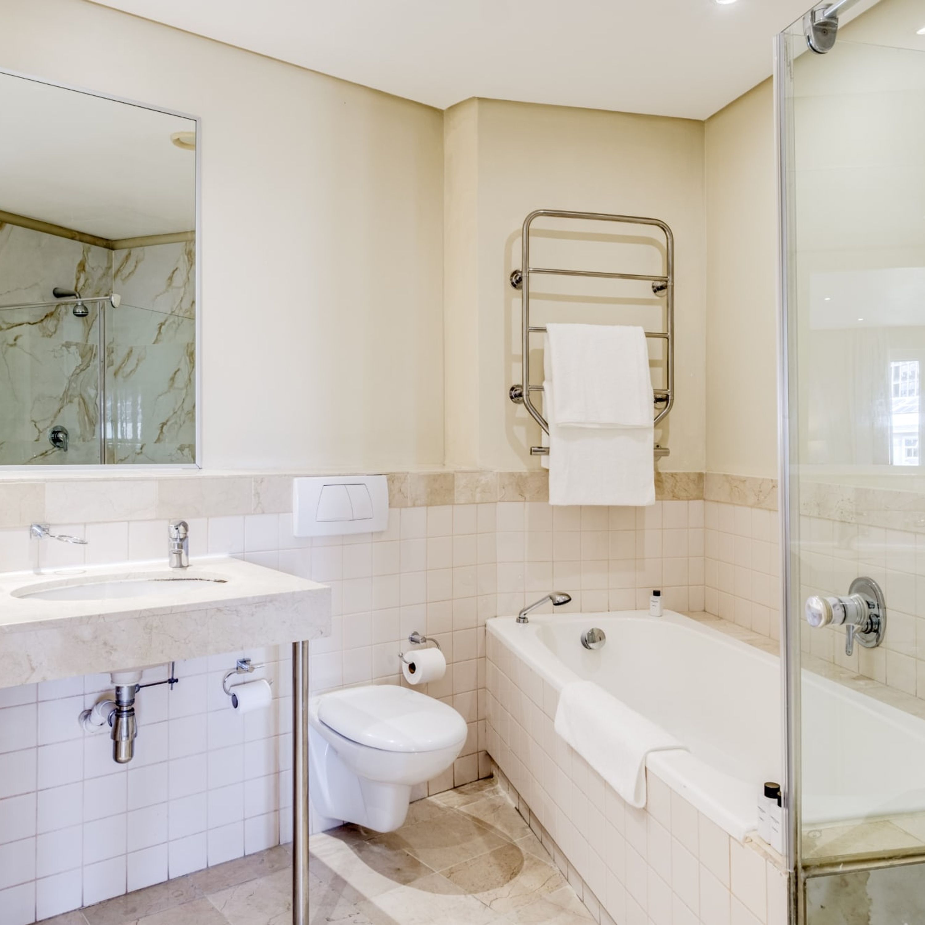 Un baño moderno con ducha envuelta en vidrio, bañera, inodoro y lavabo.
