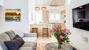 Una sala de estar moderna con un sofá, una mesa de centro y un cuadro de una escena costera.