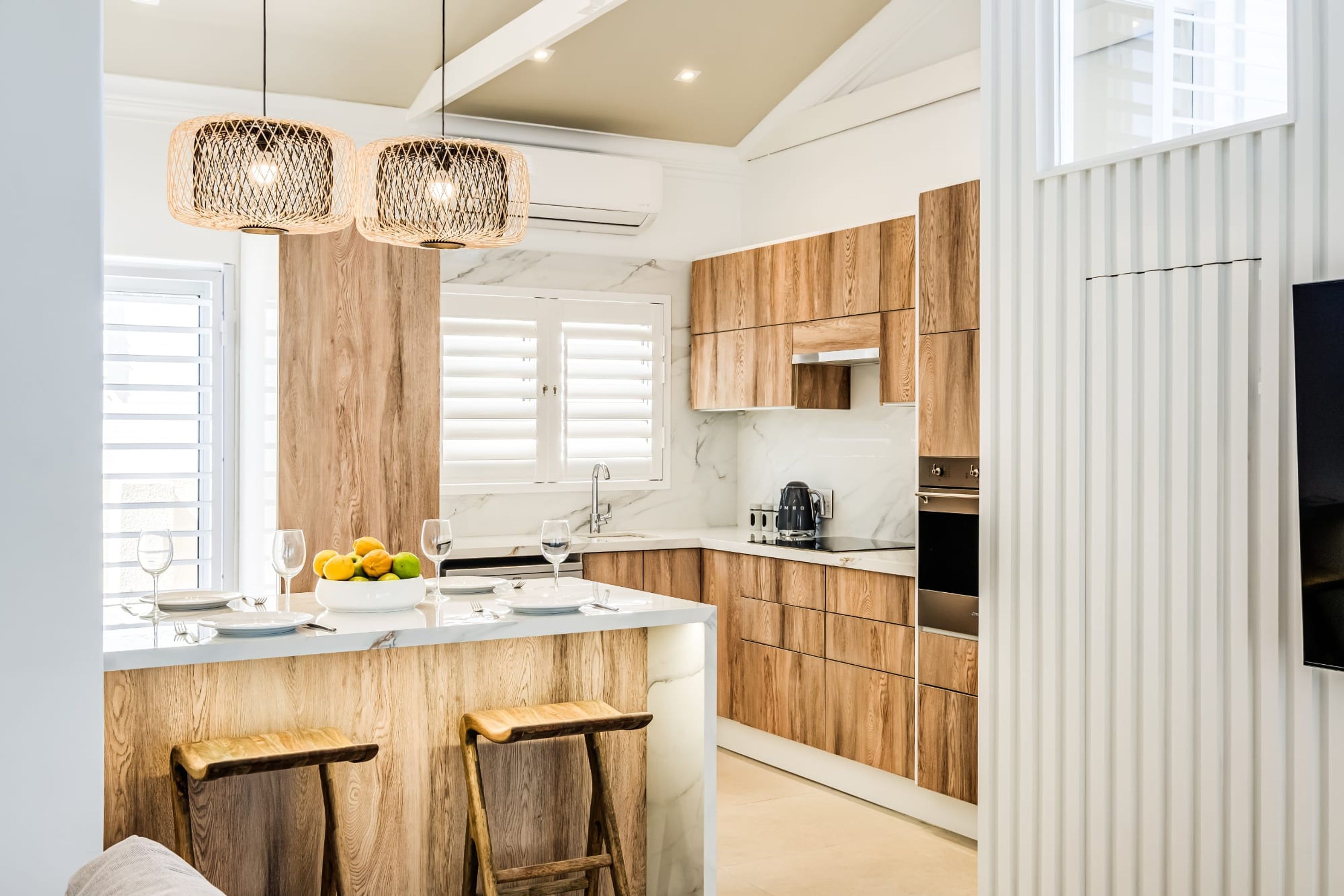 A modern kitchen with wooden cabinets, a marble countertop, and a built-in oven.