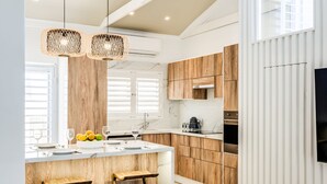 Una cocina moderna con armarios de madera, encimera de mármol y horno empotrado.