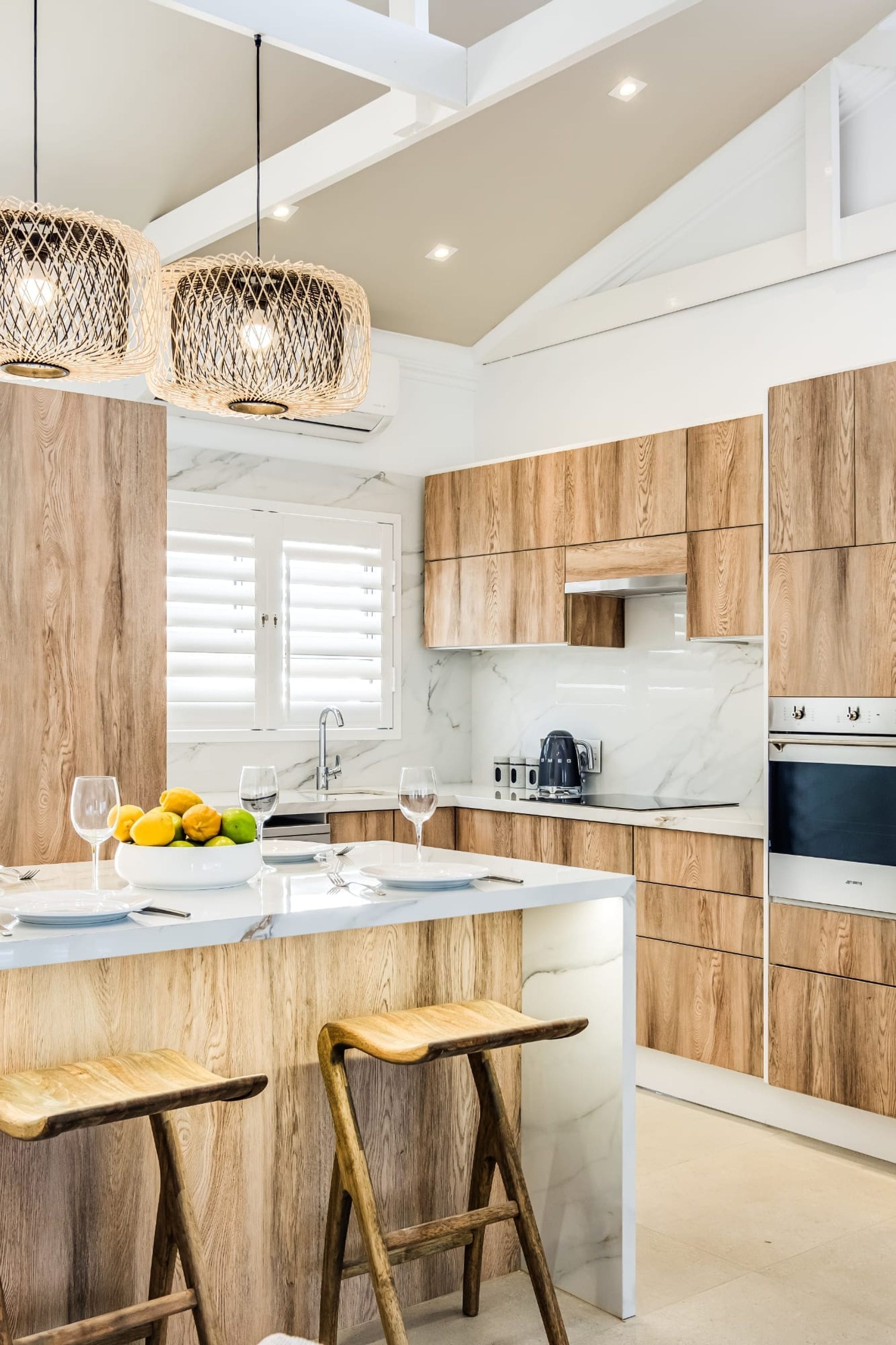 A modern kitchen with wooden cabinets, a marble countertop, and a central island with bar stools.