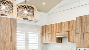 Una cocina moderna con armarios de madera, encimera de mármol y una isla central con taburetes de bar.