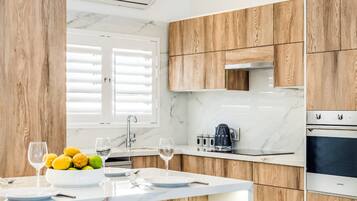 A modern kitchen with wooden cabinets, a marble countertop, and a central island with bar stools.