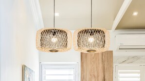 Una cocina con una isla de madera, dos l ámparas colgantes de mimbre y un frutero.