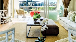 A modern living room with a sofa, chairs, a coffee table, and a view of a building through large windows.