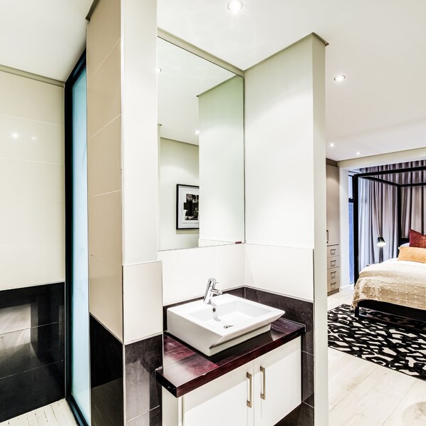 A modern bathroom with a white sink, dark marble countertop, and a large mirror. - Luxurious Villa w Sea City Views Splendor Views (Cape Town)