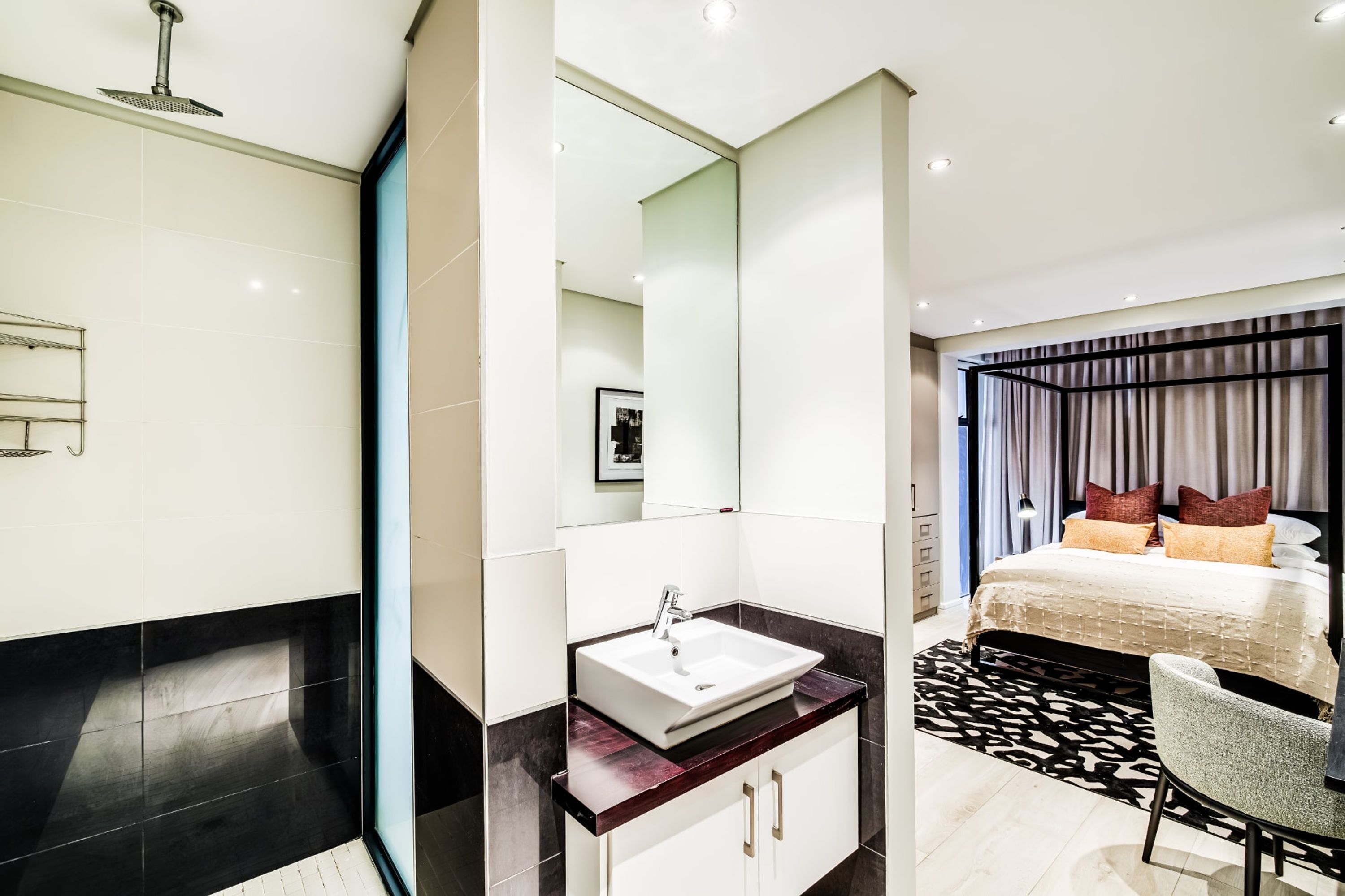Una moderna camera d'albergo con un letto grande, un bagno con lavandino e specchio.