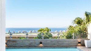 A modern outdoor pool area with a view of the ocean and city skyline. - Luxurious Villa w Sea City Views Splendor Views (Cape Town)