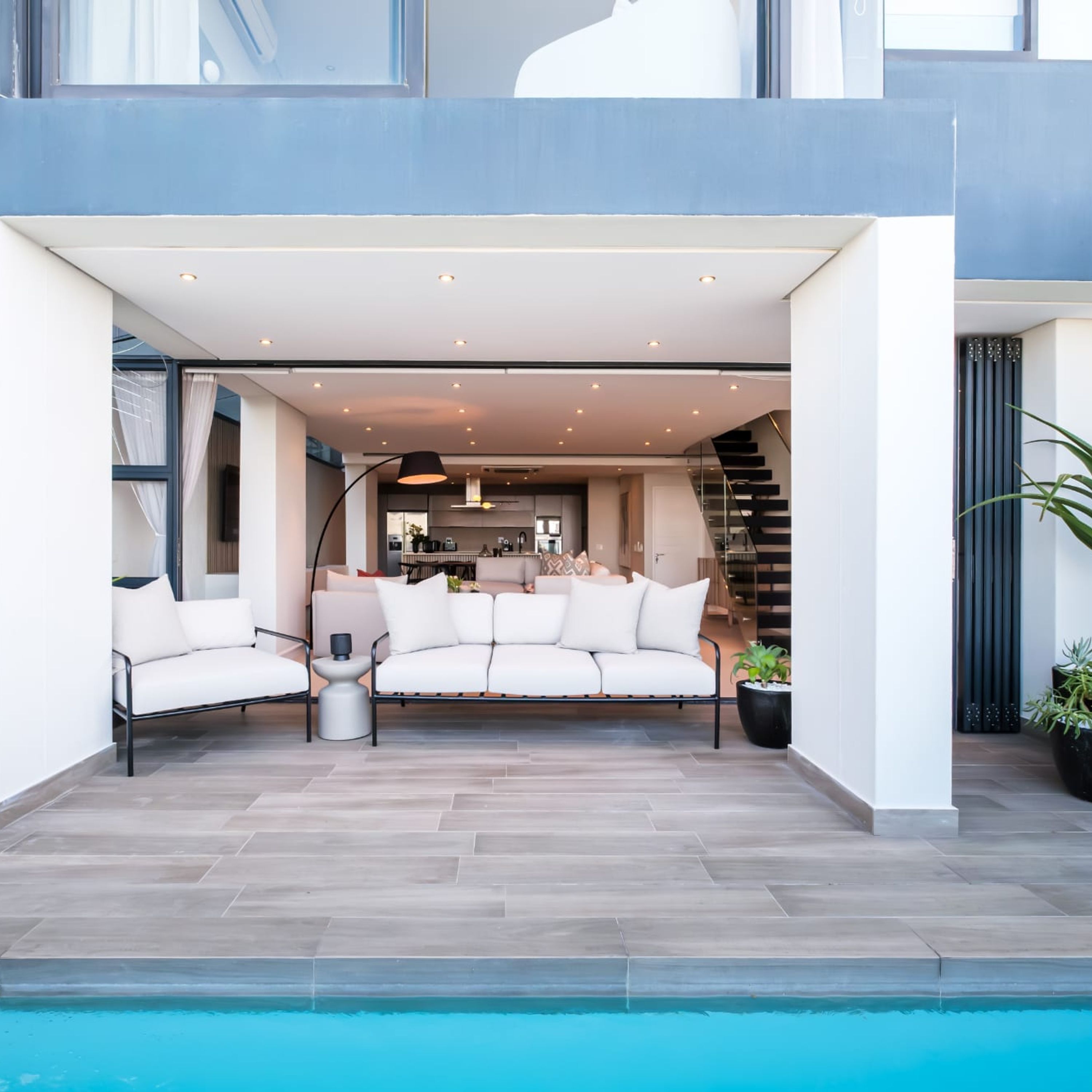 Un espace de vie extérieur moderne comprenant une piscine, un canapé et un escalier.