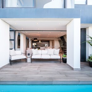 A modern outdoor living area with a pool, a sofa, and a staircase.