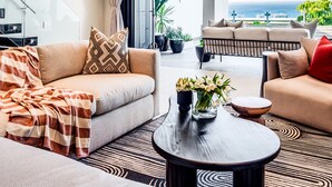 A modern living room with a sofa, a coffee table, and a view of the ocean. - Luxurious Villa w Sea City Views Splendor Views (Cape Town)