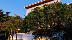 A staircase leading to a building with a white exterior and a wooden roof. - Luxurious Camps Bay Retreat w Sea Views Rock Residence (Cape Town)