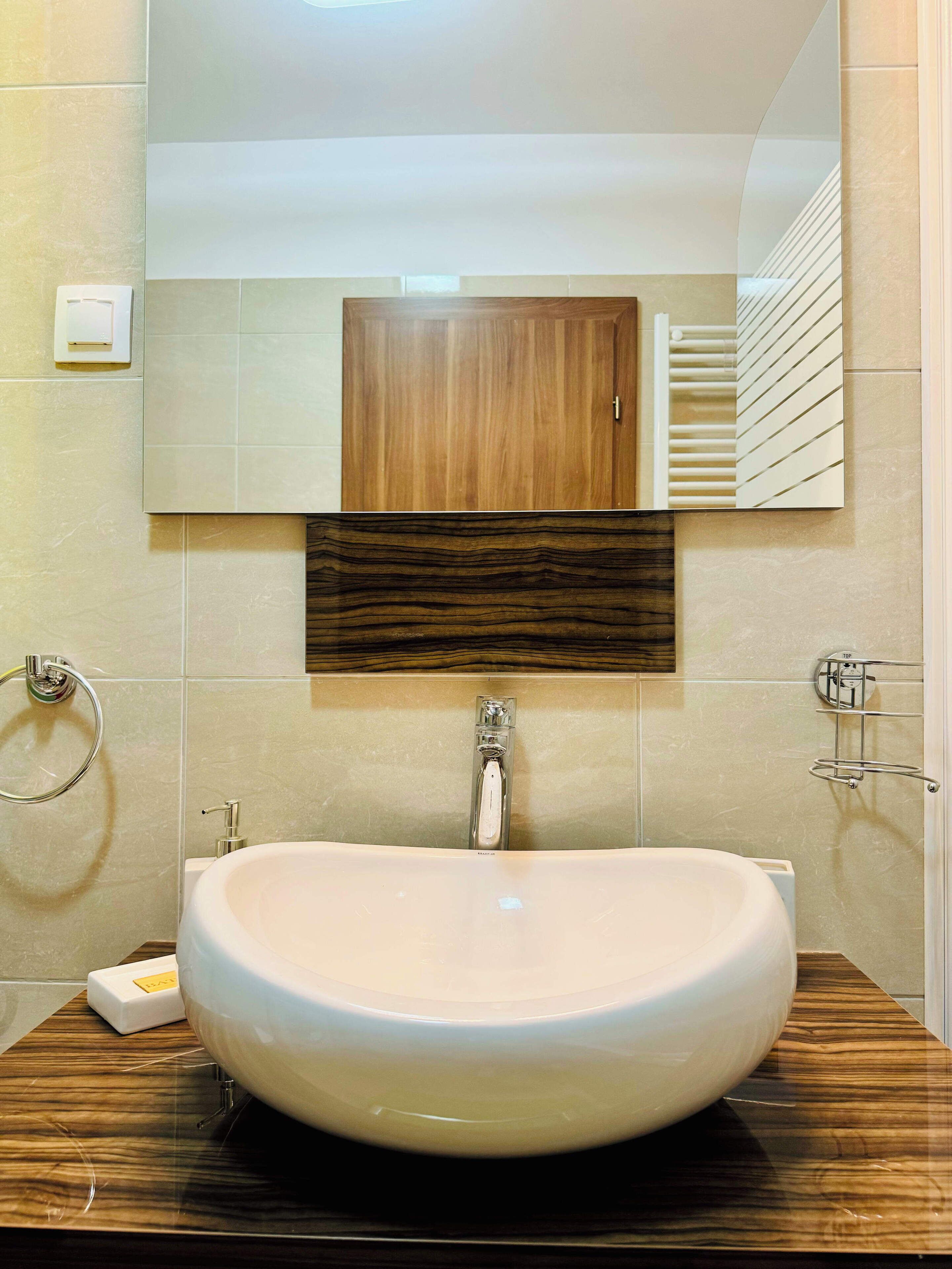A bathroom with a large oval sink, a wooden cabinet above the mirror, and a towel rack on the wall.