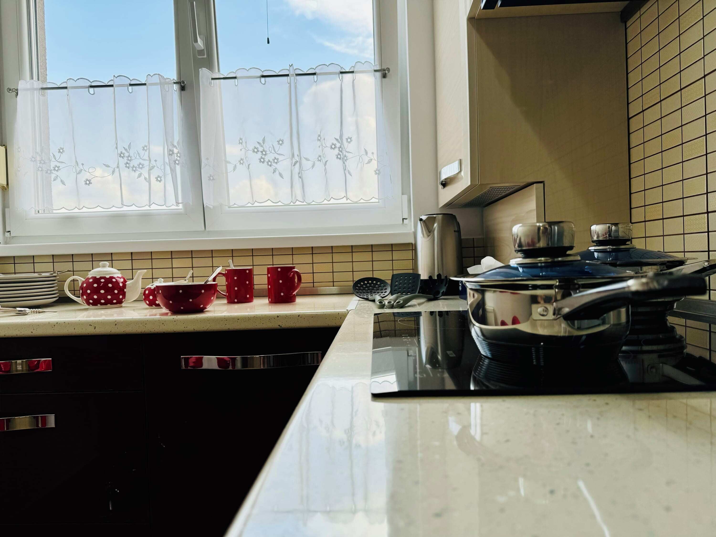Een keuken met een raam, een fornuis en keukengerei op het aanrecht.