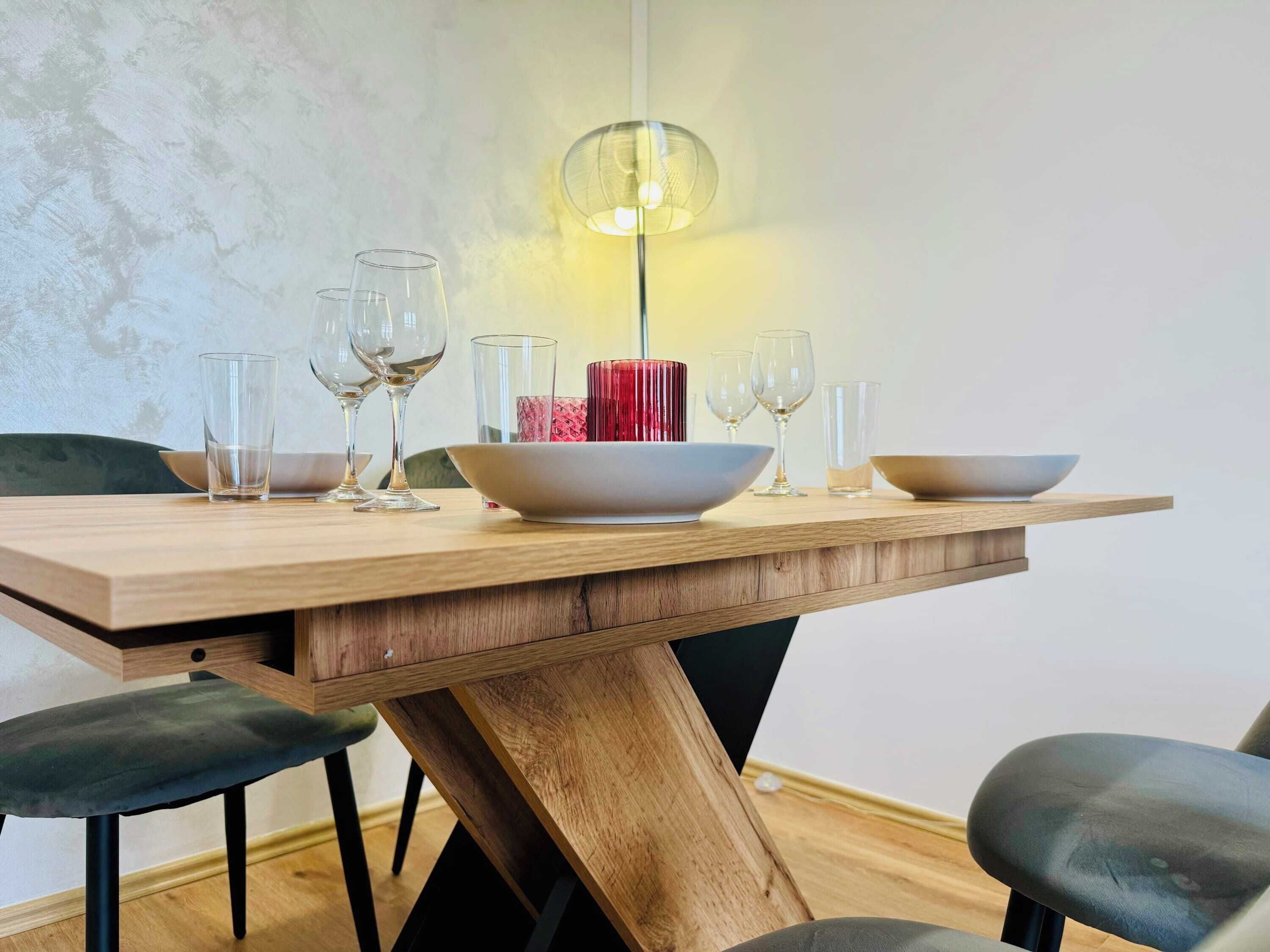 Een eettafel met vier stoelen, een rode vaas in het midden en een hanglamp.