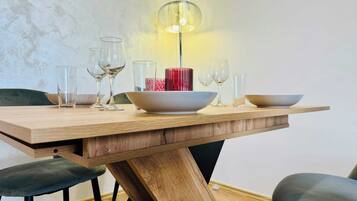 Een eettafel met vier stoelen, een rode vaas in het midden en een hanglamp.