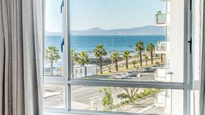 Un dormitorio con un ventanal que ofrece vistas al mar y una montaña distante.