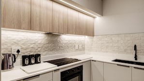 Una cocina moderna con armarios blancos, estufa negra y encimera blanca.