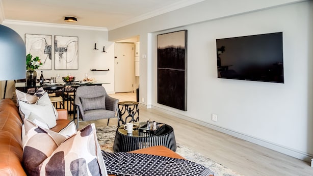 Una sala de estar moderna con un sofá de cuero, una mesa de centro y un comedor con una silla y una mesa.