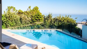 A pool area with lounge chairs and a view of the sea. - Sea View Sanctuary at Shakawe Villa (Cape Town)