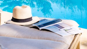 A poolside lounge with a hat and magazine on a lounge chair, surrounded by greenery. - Sea View Sanctuary at Shakawe Villa (Cape Town)