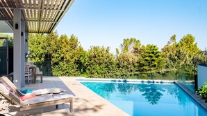 A modern outdoor pool area with a lounge chair and a table, surrounded by lush greenery. - Sea View Sanctuary at Shakawe Villa (Cape Town)