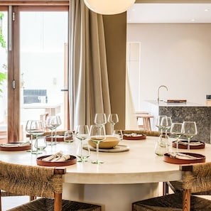 A dining area with a round table set for six, surrounded by wicker chairs.