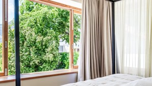 Ein Schlafzimmer mit großem Fenster, einem Himmelbett und Vorhängen.