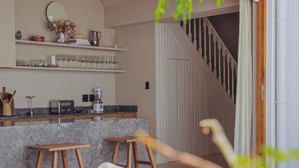 Eine moderne Küche mit Granit Arbeitsplatte, einer Kaffeemaschine und einem Weinkühlschrank. Eine Treppe führt zu einem Balkon.