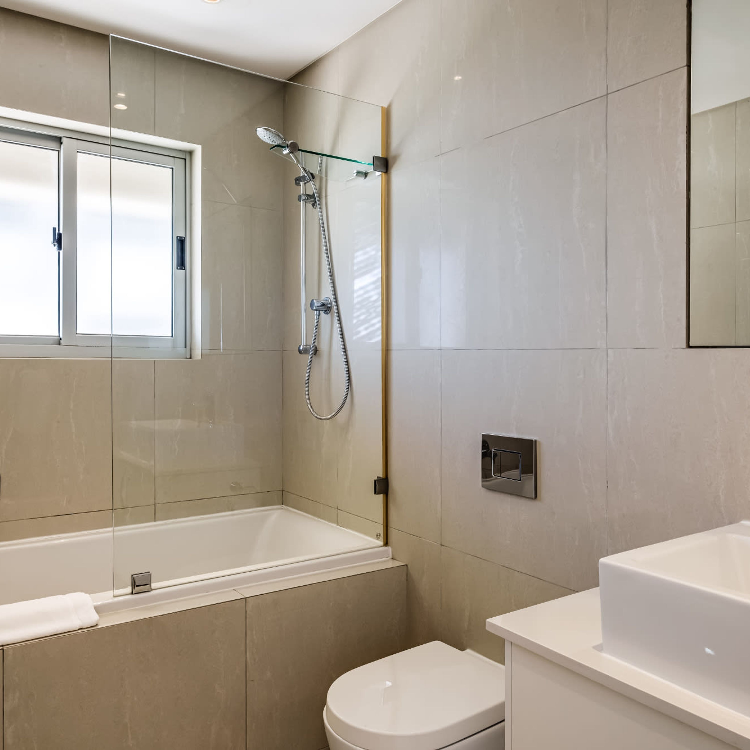 A modern bathroom with a bathtub, toilet, and shower.