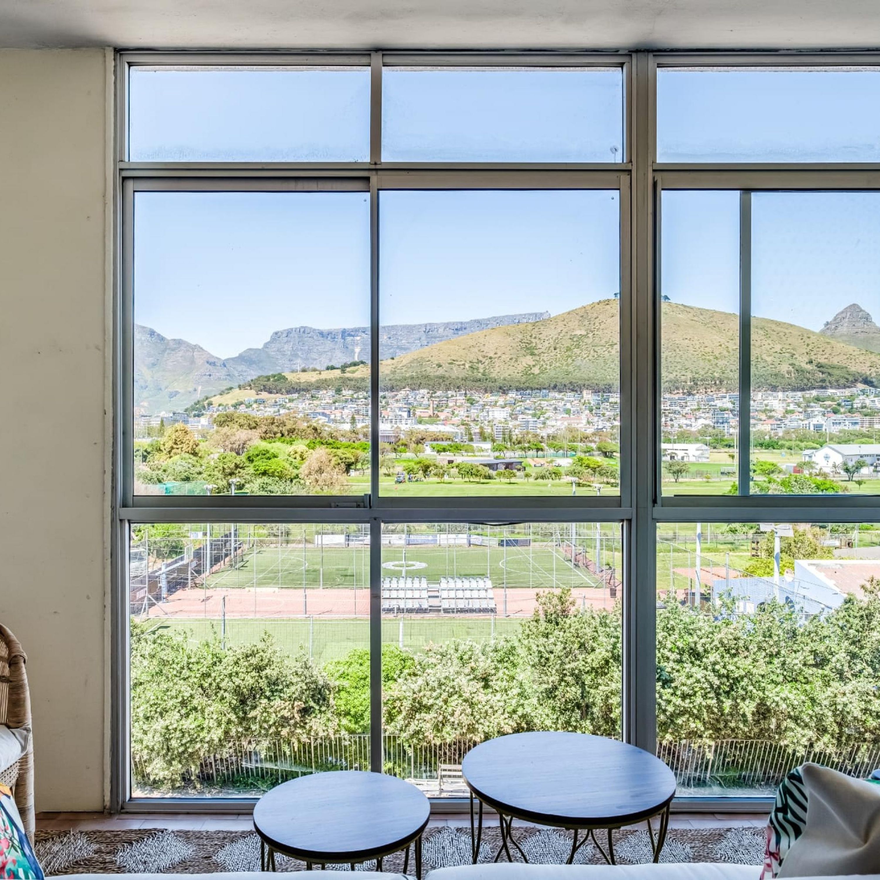 Ein Zimmer mit großen Fenstern und Blick auf eine Wohngegend sowie ein Sportplatz.