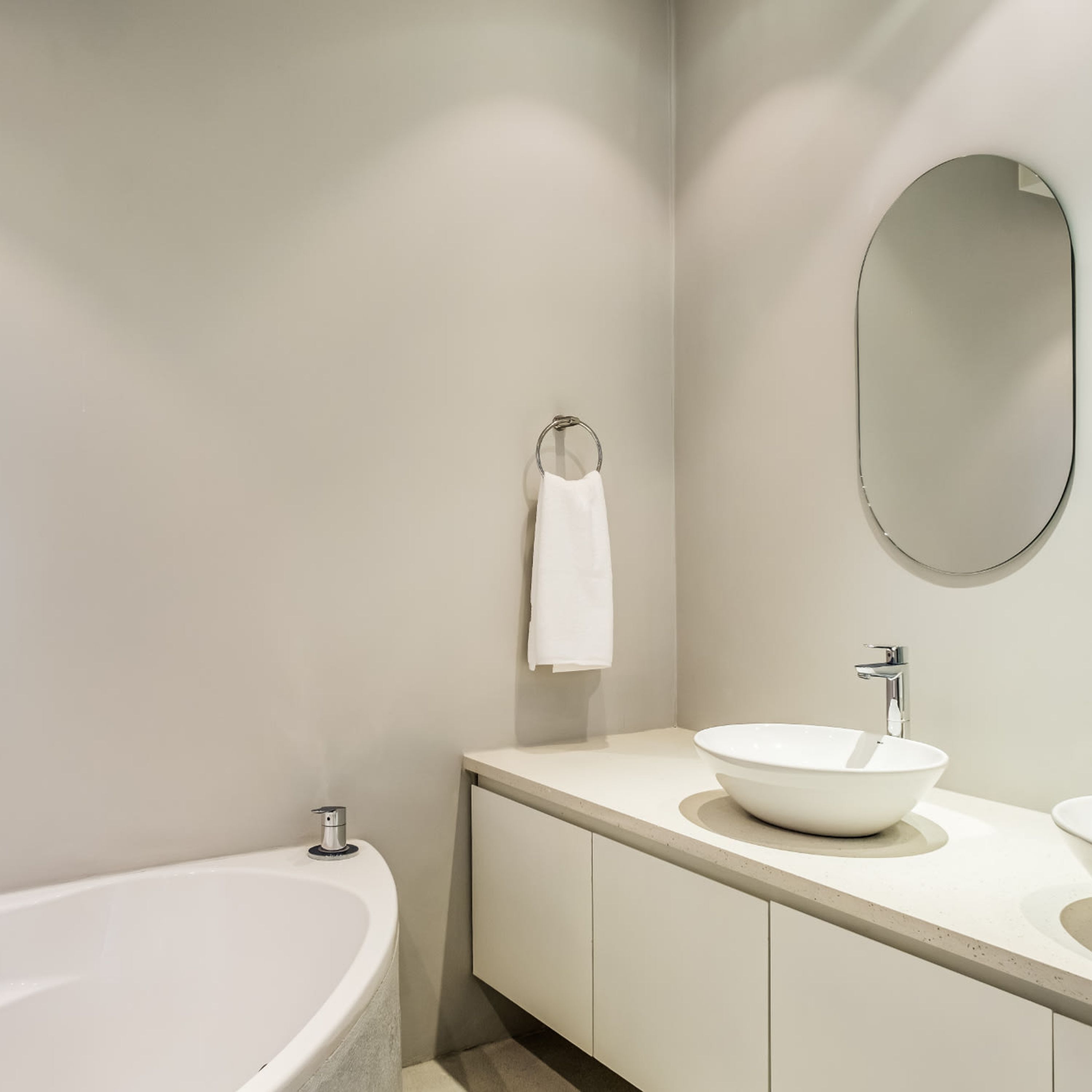 Un bagno moderno con una vasca freestanding, uno specchio rotondo e un lavandino con bacino a vista.