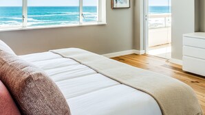 A bedroom with a large window overlooking the ocean, a bed, and a door leading to a balcony. - Picturesque Seaside Haven Aretzi (Cape Town)