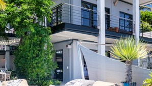 A swimming pool with beige lounge chairs and a potted plant. - Elegant Charm Retreat Central Treasure (Cape Town)