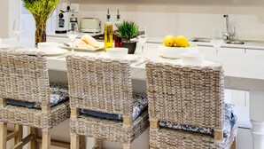 A modern kitchen with white cabinets, a dining table set with chairs, a vase of flowers, and a fruit bowl. - Elegant Charm Retreat Central Treasure (Cape Town)