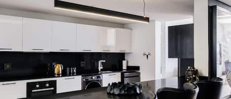 A modern kitchen with a central island, black bar stools, and a black countertop.