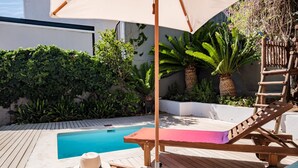 A wooden deck with a pool, lounge chairs, and a hat on the table. - Modern Elegance Meets City Serenity at Meliora (Cape Town)