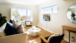 A living room with a sofa, chairs, a coffee table, and a TV mounted on the wall. - Modern Elegance Meets City Serenity at Meliora (Cape Town)