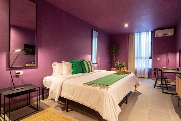 A bedroom with a bed, bedside table, lamp, and a desk with a chair. - Colorful Lively Centro Gem 5BR Rooftop Patio (San Miguel de Allende)