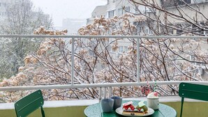 A balcony with a green table and two green chairs, a plate of food, and a decorative item. - Holt - Out of the Woods (Bucharest)