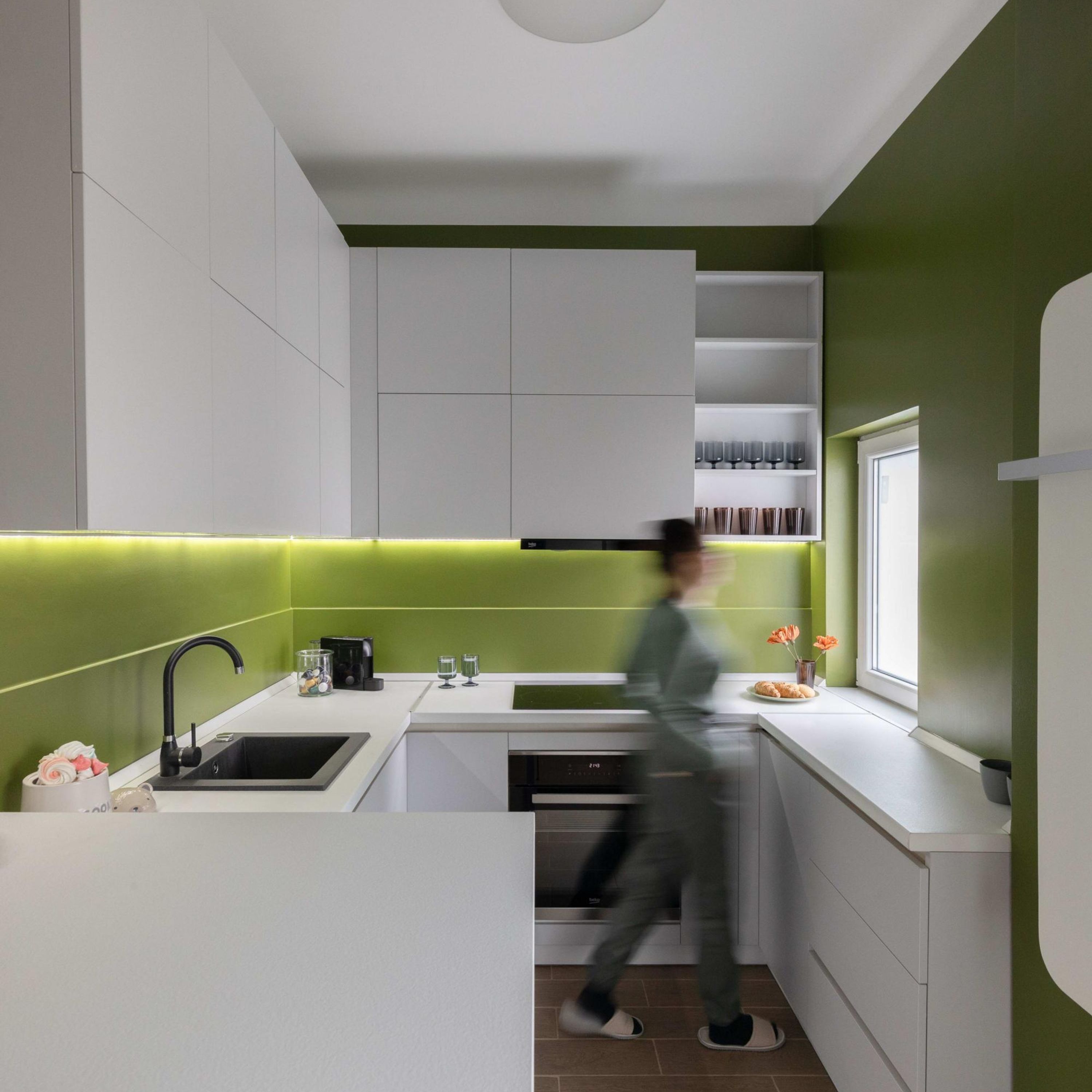 A modern kitchen with white cabinetry, a black faucet, and a window with a view.