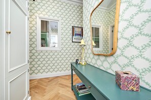 A room with patterned wallpaper, a mirror, a desk with books, and a tissue box. - Charming 1 Bedroom 1 Bathroom Notting Hill (London)
